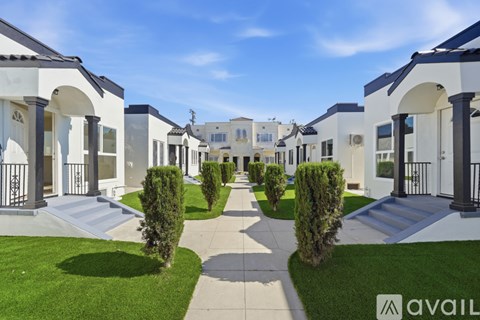 A row of houses with green lawns and a clear blue sky.