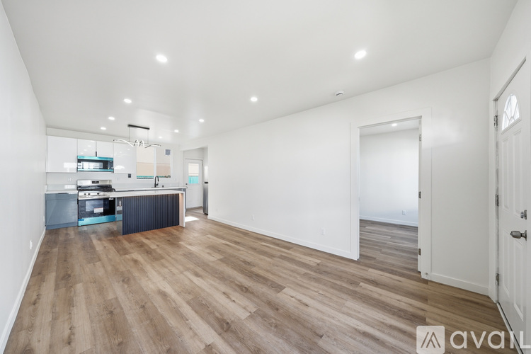 A spacious room with wooden flooring and white walls.