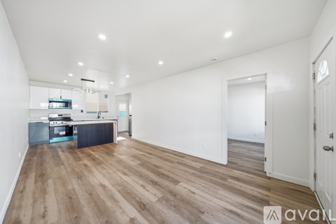 A spacious room with wooden flooring and white walls.