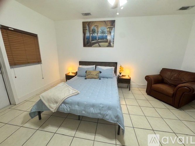 A bedroom with a bed, a couch, and a painting on the wall.