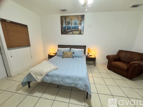 A bedroom with a bed, a couch, and a painting on the wall.