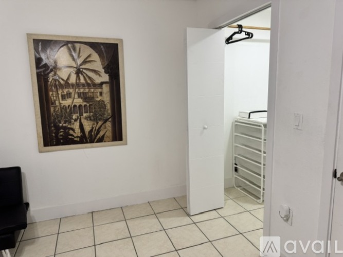 A room with a picture of a building on the wall and a black chair.