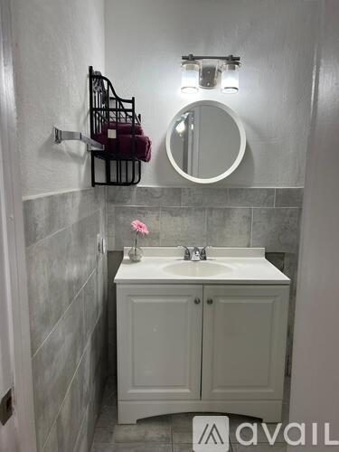 A bathroom with a white sink and a round mirror.