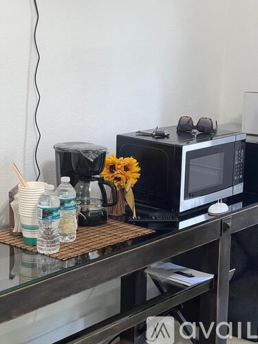 A black microwave with a vase of flowers on top of a glass table.