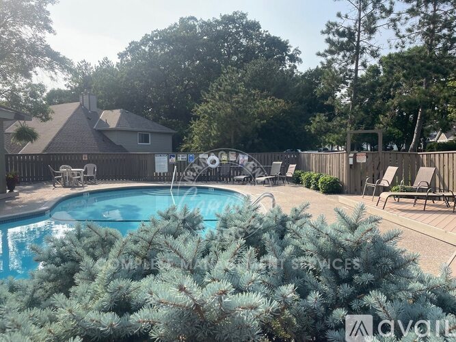 A pool surrounded by trees and chairs.