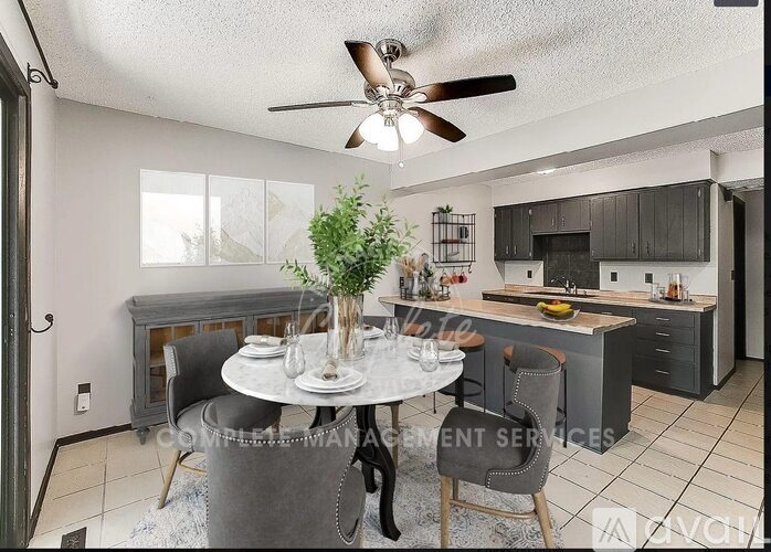 A dining room with a table set for two and a kitchen in the background.
