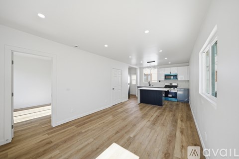 A spacious kitchen with wooden floors and white walls.