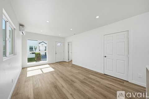 A spacious room with wooden floors and white walls.