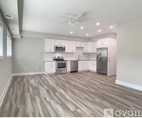 A kitchen with white cabinets and a wooden floor.