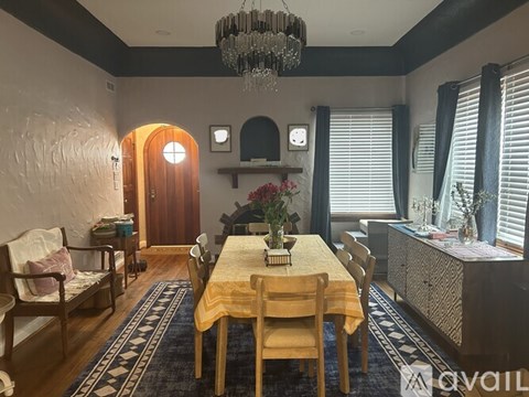 A dining room with a table set for four and a chandelier hanging from the ceiling.