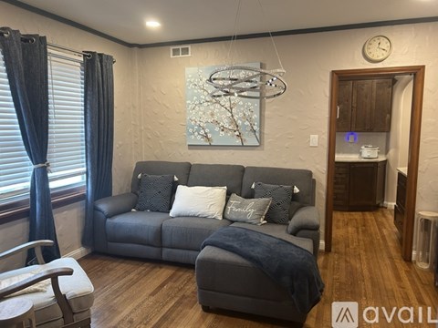 A living room with a grey couch and a painting on the wall.
