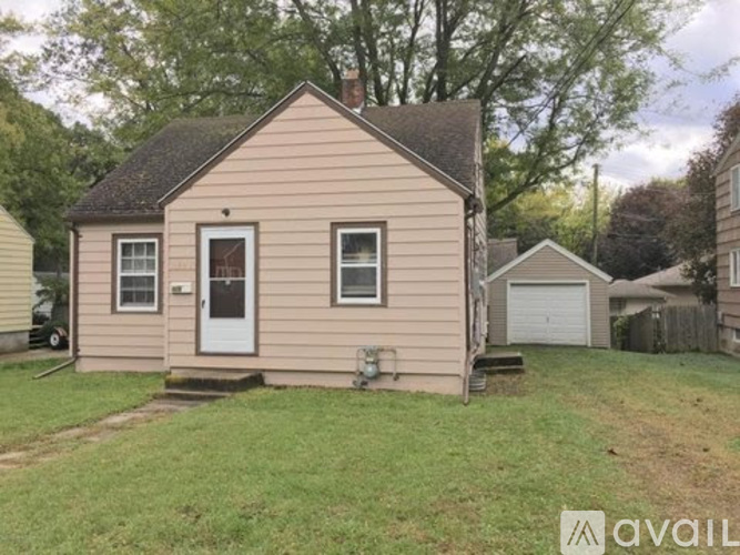 A small house with a white door and two windows is for sale.