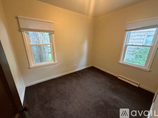 A room with two windows and carpeted floor.