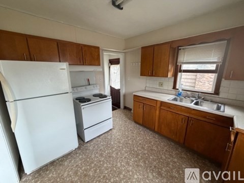 A kitchen with a white refrigerator, brown cabinets, and a sink.