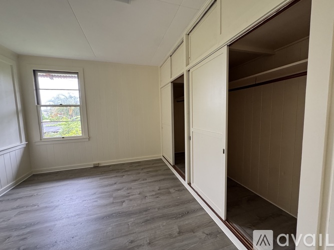 A room with a window and a wooden floor.