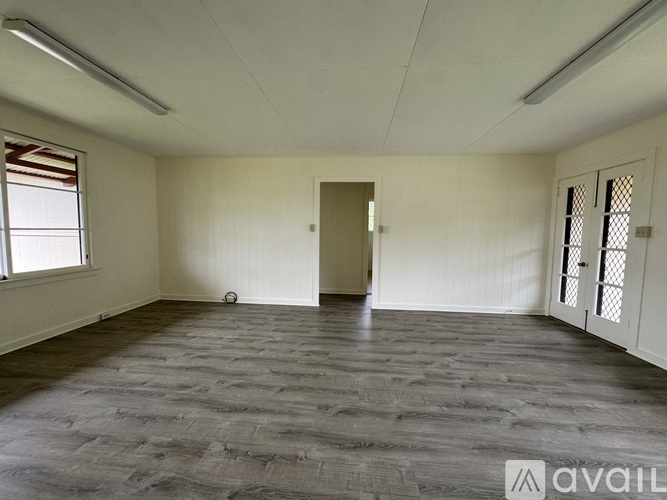 A spacious room with wooden flooring and white walls.