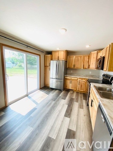 A kitchen with wooden cabinets and a grey floor.