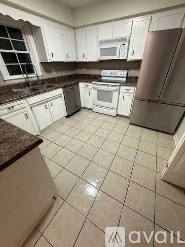 A kitchen with white cabinets and a refrigerator.