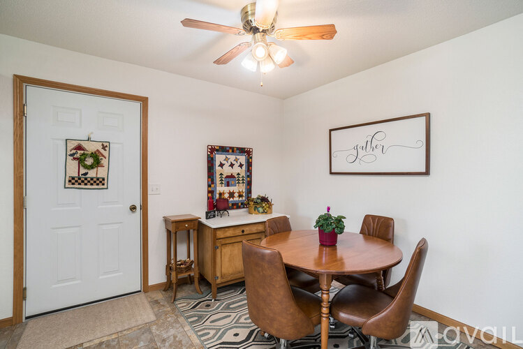 A dining room with a table set for two and a framed picture on the wall.