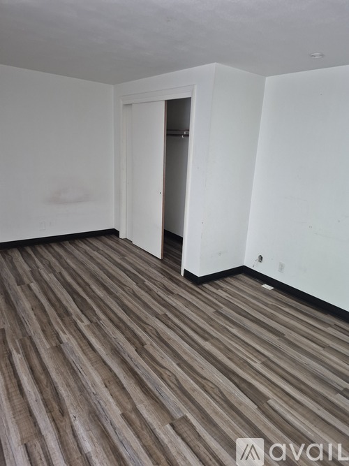 A room with wooden flooring and white walls.