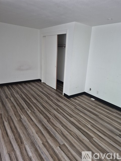 A room with wooden flooring and white walls.