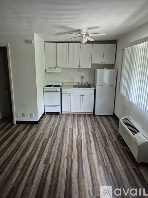 A kitchen with white appliances and wooden floors.