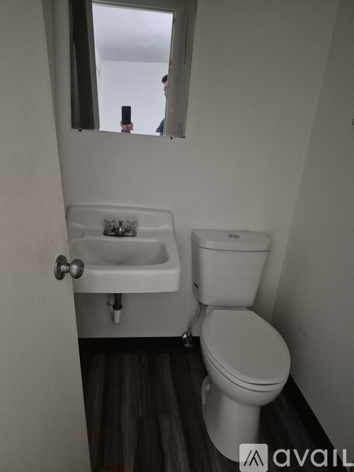 A bathroom with a toilet, sink, and mirror.