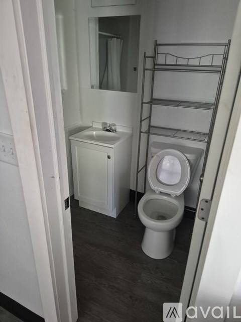 A white toilet with a white cabinet and a mirror above it.