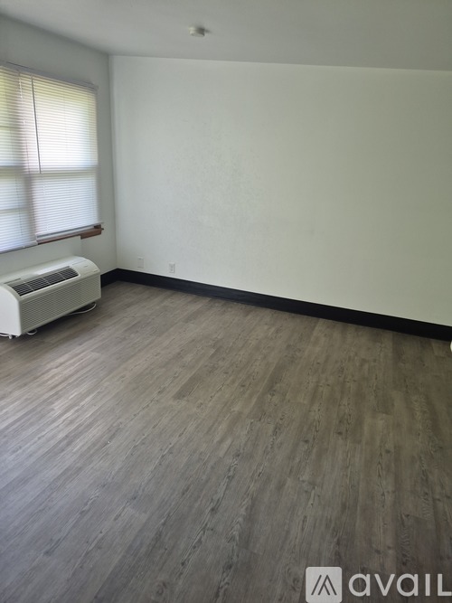 A room with wooden flooring and a window with blinds.