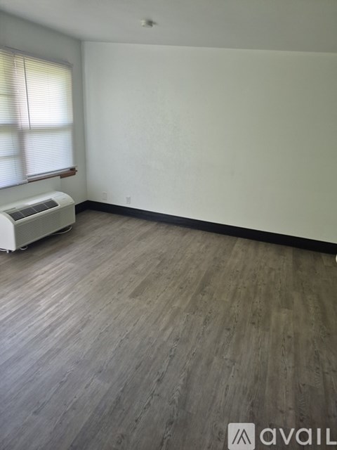 A room with wooden flooring and a window with blinds.
