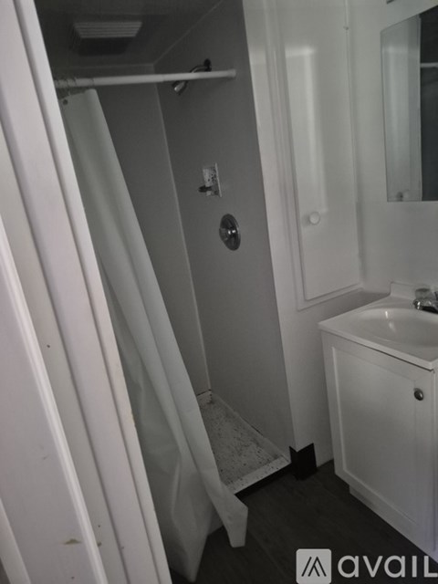 A small white bathroom with a sink and a shower.