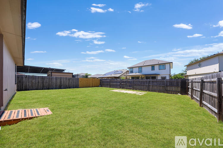 A backyard with a wooden fence and a small patch of grass.