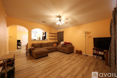 A living room with a brown sofa and a wooden floor.