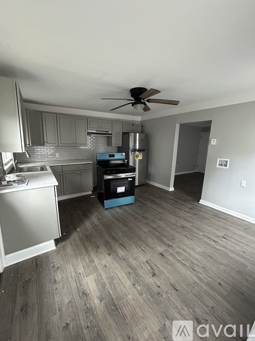 A kitchen with a fan on the ceiling and a wooden floor.