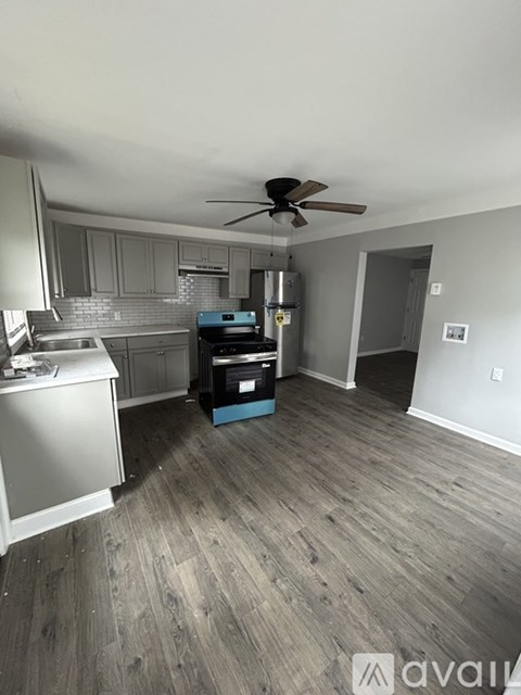 A kitchen with a fan on the ceiling and a wooden floor.