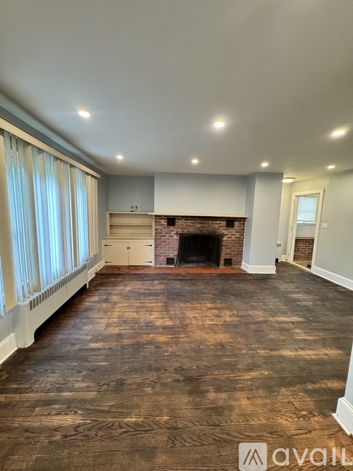 A spacious room with a fireplace and wooden flooring.