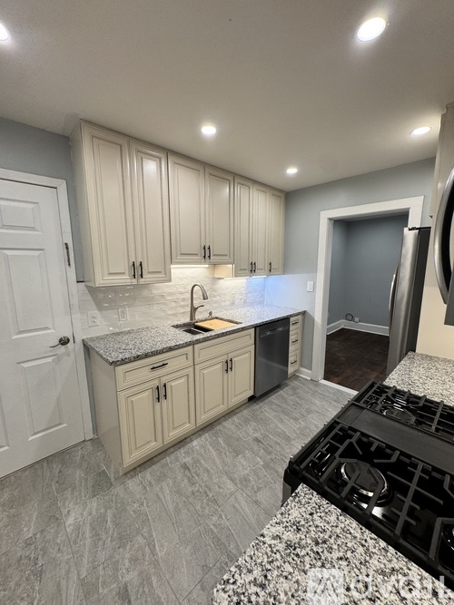 A kitchen with a black stove top oven and white cabinets.