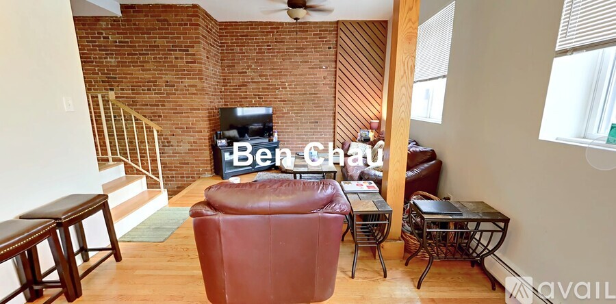 A living room with a red leather chair and a brick wall.