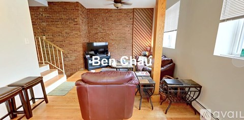 A living room with a red leather chair and a brick wall.