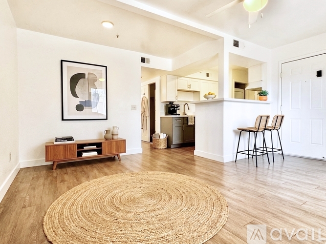 A living room with a rug on the floor and a bar area in the background.