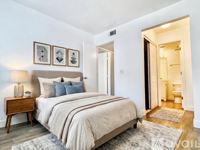 A bedroom with a large bed and a nightstand with a lamp.
