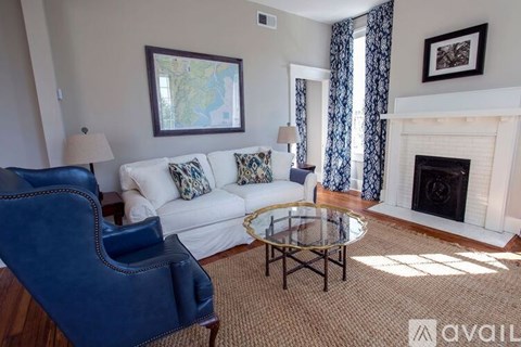 A living room with a white couch, a blue chair, and a fireplace.