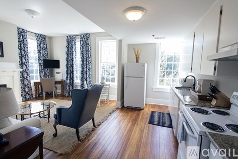 A kitchen with a refrigerator, stove, and a dining table with chairs.