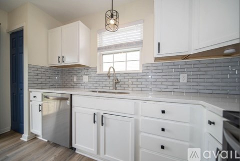 A kitchen with white cabinets and a brick backsplash.
