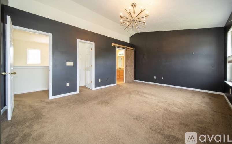 A room with a carpeted floor and a chandelier hanging from the ceiling.