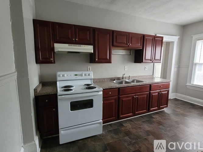 A kitchen with brown cabinets and a white stove top oven.