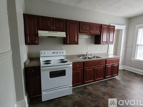 A kitchen with brown cabinets and a white stove top oven.