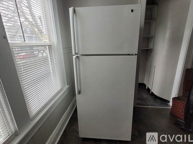 A white refrigerator in a room with a window.