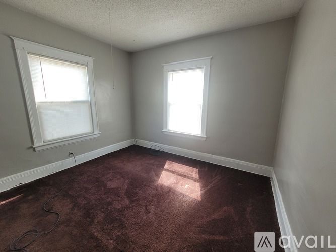 A room with two windows and a carpeted floor.
