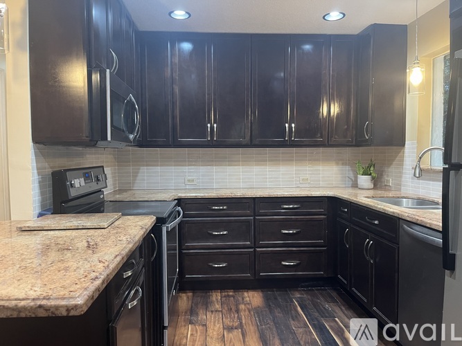 A kitchen with black cabinets and a granite countertop.